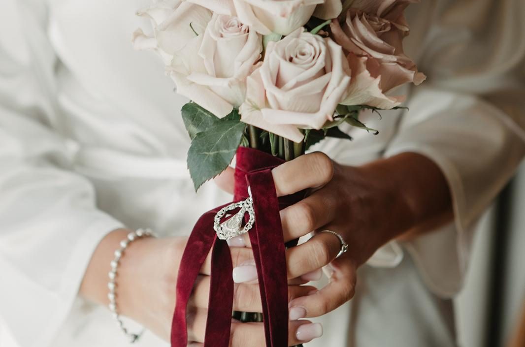 Ramo de flores blancas y verdes sostenido por una mujer con vestido claro.